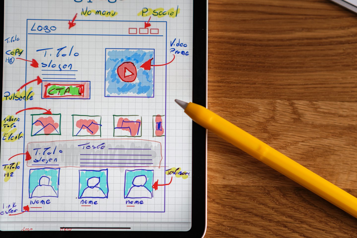 Cyfrowy tablet z projektami stron internetowych na drewnianym stole.